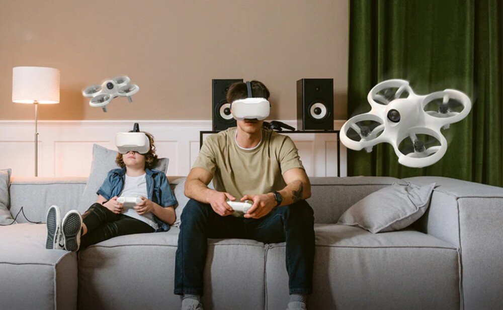 Dron BETAFPV Cetus Lite FPV Kit Dwoje użytkowników siedzących na kanapie w goglach FPV, sterujących dronami latającymi w salonie