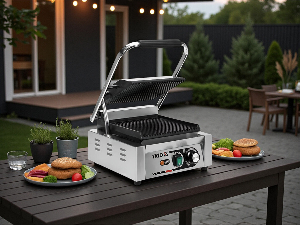 Grill elektryczny YATO YG-04555, kuchnia, grillowanie, potrawy, smażenie, Otwarty grill YATO YG-04555 na ogrodowym stole, wokół talerze z burgerami, warzywami i pieczywem, widok na taras.