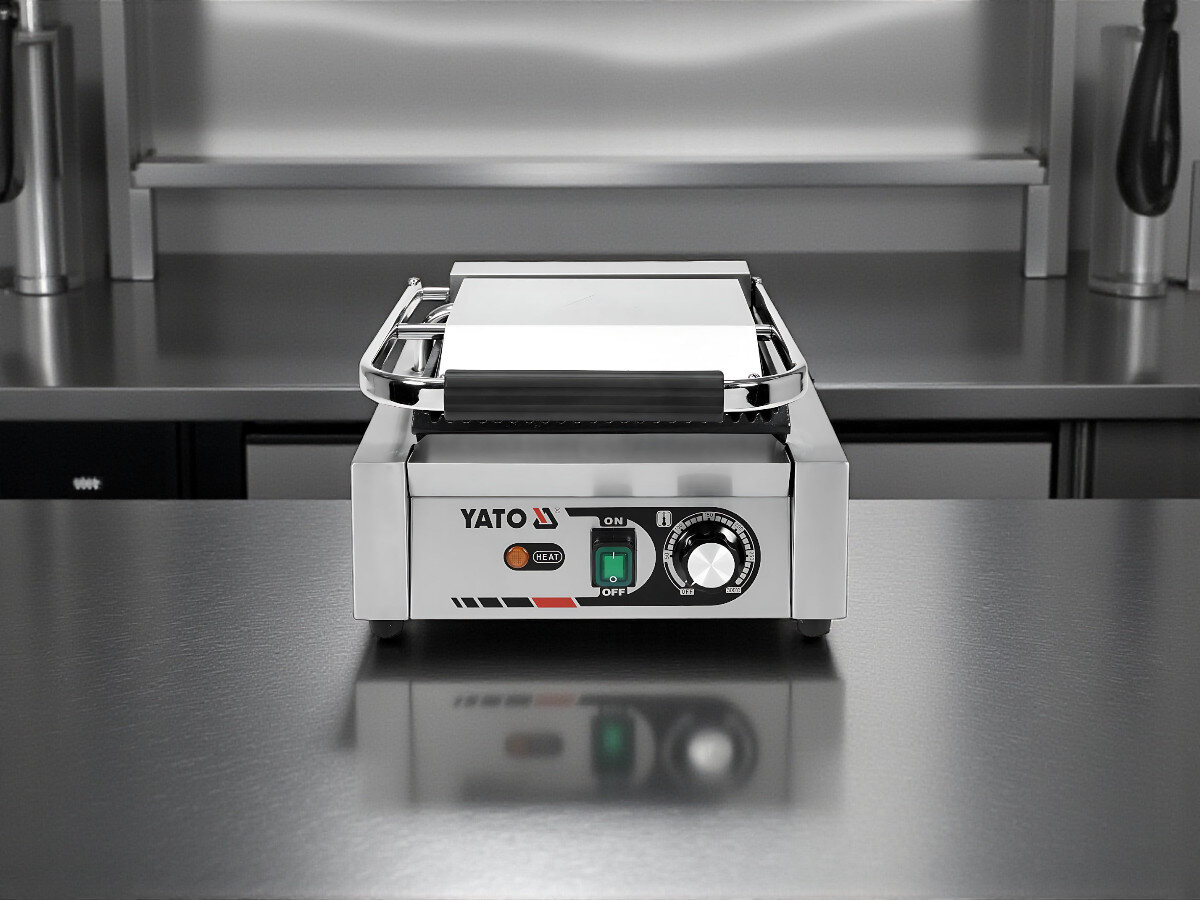 Grill elektryczny YATO YG-04555, ryflowana płyta, żeliwo, kuchnia, smażenie, Grill elektryczny YATO YG-04555 w pozycji zamkniętej, ustawiony na stalowym blacie profesjonalnej kuchni.