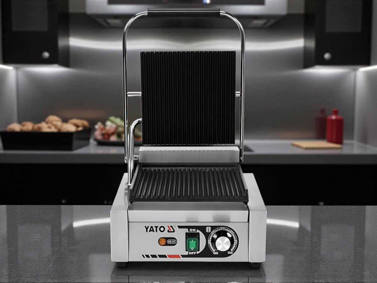Grill elektryczny YATO YG-04555, uchwyt, bezpieczeństwo, ergonomia, lampka, Grill YATO YG-04555 w pozycji otwartej, widok frontalny na stalowym blacie, w tle wyposażenie kuchni.
