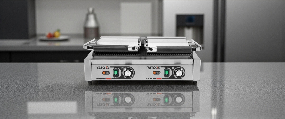 Grill elektryczny YATO YG-04560, bezpieczeństwo, kontrolki, uchwyty, komfort, Grill YATO YG-04560 w pozycji zamkniętej widok z przodu na kuchennym blacie, lustrzane odbicie na powierzchni.