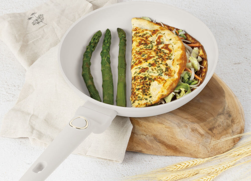 Patelnia BERLINGER HAUS Sahara Collection BH 8054 28 cm kremowa patelnia ustawiona na podstawce potrawa w środku patelni kremowy uchwyt złote elementy jasne tło do każdej kuchni 