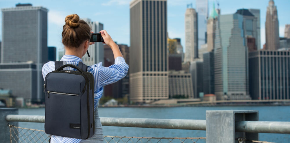 Plecak na laptopa SAMSONITE Litepoint 17,3 cali Granatowy
przemyślany design, kanciasta bryła, stonowana kolorystyka,
lekka konstrukcja ok. 1,3 kg, kompaktowe wymiary ok. 46 x 32 x 18 cm, pojemność 18 litrów,
kobieta z założonym plecakiem, robiąca zdjęcie miasta