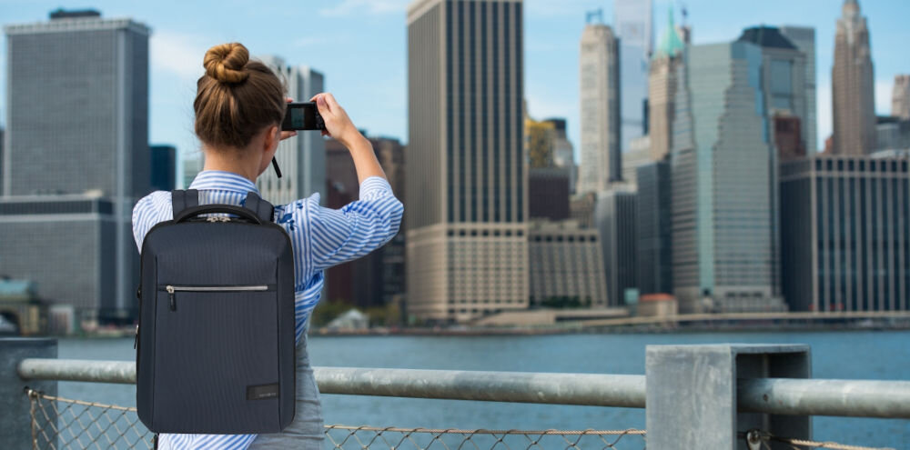 Plecak na laptopa SAMSONITE Litepoint 15,6 cali Granatowy
przemyślany design, kanciasta bryła, stonowana kolorystyka,
lekka konstrukcja ok. 900 g, kompaktowe wymiary ok. 43 x 30 x 13 cm, pojemność 18 litrów,
kobieta z założonym plecakiem, robiąca zdjęcie miasta