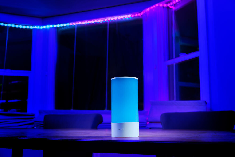 Lampa RAZER Aether Smart Lamp Regulacja jasności, Wi-Fi, Bluetooth prezentacja lampy na stole na tle pokoju z oświetleniem ledowym