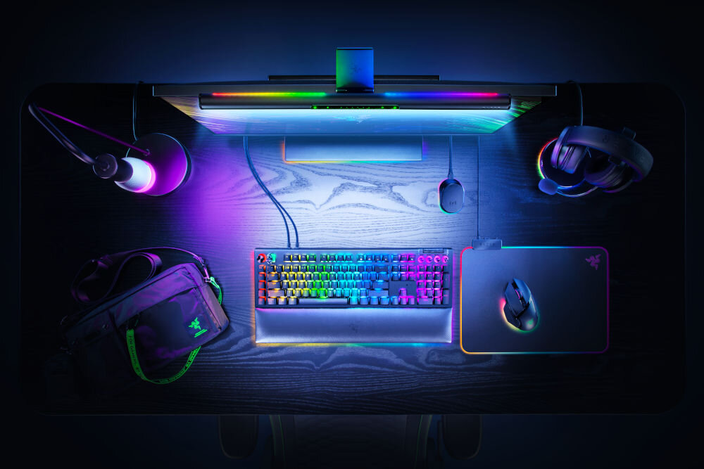 Lampka na monitor RAZER Aether Monitor Light Bar 10 W, Regulacja jasności, Wi-Fi prezentacja lampy przymocowanej do monitora na biurku i jej oświetlenia od góry funkcjonalność klimat podwójne oświetlenie białe diody LED z przodu regulowany kąt świecenia diody RGB z tyłu efekty Razer Chroma™ immersyjne tło