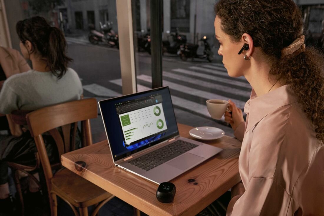 Laptop HP EliteBook 860 - Kobieta pracująca przy stole z laptopem HP EliteBook 860, otoczona przyjemną atmosferą.