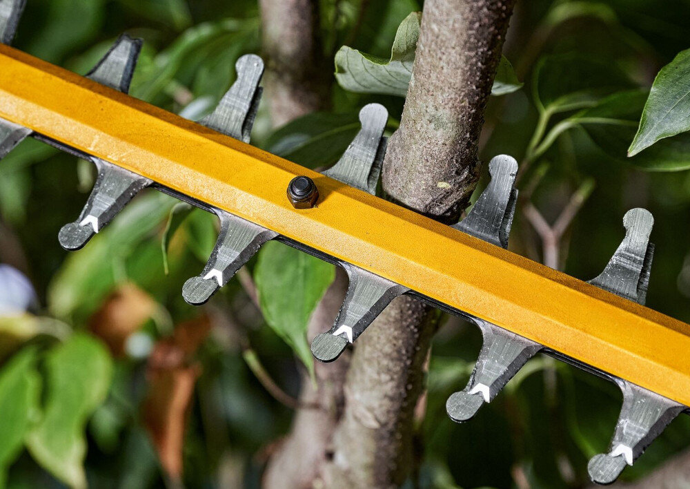 Nożyce do żywopłotu DEWALT DCMHT573N-XJ 650mm 54V akumulatorowe zbliżenie na ostrza gałęzie ostrza zaczepione o gałęzie ostrze o długości 66 cm odstęp między ostrzami 31 mm szybkie przycinanie cienkich i gęstszych gałęzi falista konstrukcja ostrza stabilizuje pędy równe linie cięcia i estetyczny efekt końcowy