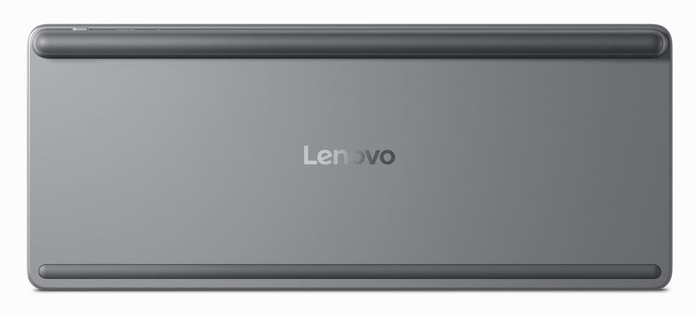 Obraz przedstawia tylną część klawiatury w kolorze szarym z widocznym logo \'Lenovo\' na środku. Na górze i dole znajdują się podłużne gumowe elementy antypoślizgowe.