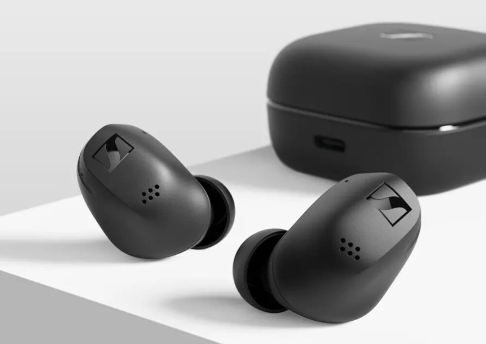 Słuchawki dokanałowe SENNHEISER Accentum True Wireless ANC Dwie czarne bezprzewodowe słuchawki douszne leżą obok zamkniętego etui ładującego na białej powierzchni, mikrofony, redukcja szumów, odporność, szczelność IP54