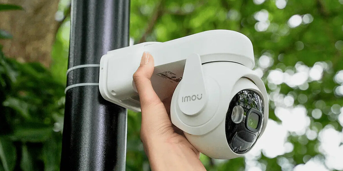 Kamera IMOU Cell PT Zewnętrzna, Wi-Fi, warunki IP66, odporność, solidne, dłoń trzyma kamerę zamontowaną do słupa