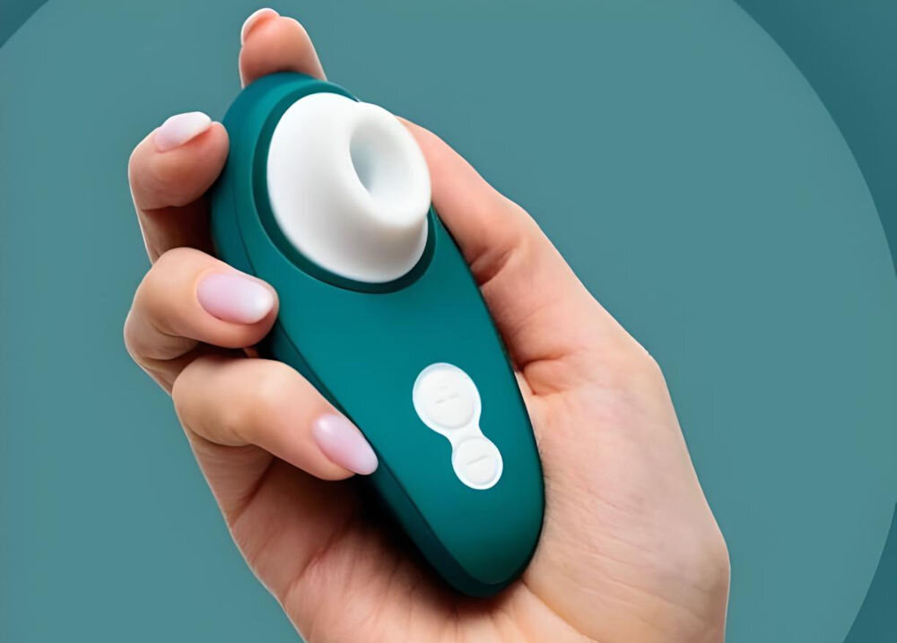 WOMANIZER Liberty 2 Dark Petrol bezdotykowy masażer łechtaczki masażer trzymany w ręce zielony ikonka wody przyciski białe elementy elegancja i technologia pełna wodoodporność klasy IPX7 wyjątkowe doznania relaksująca kąpiel w wannie odświeżający prysznic w basenie solidna konstrukcja bezproblemowe działanie pod wodą różne sposoby na przyjemność dla miłośników wodnych przygód