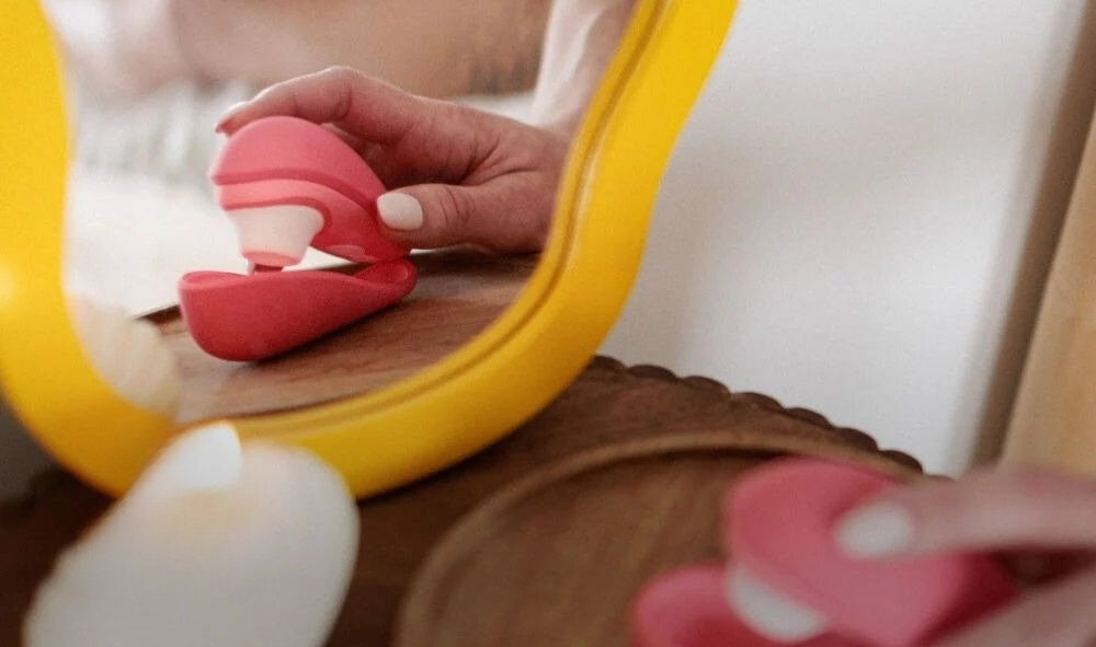 WOMANIZER Liberty 2 Vibrant Rose bezdotykowy masażer łechtaczki zamknięcie masażera na podstawce łańcuszek telefon technologia Pleasure Air intensywna stymulacja wykorzystanie pulsującego powietrza delikatnie masowana łechtaczka redukuje ryzyko nadmiernej stymulacji dłuższa komfortowa przyjemność niezapomniane wrażenia