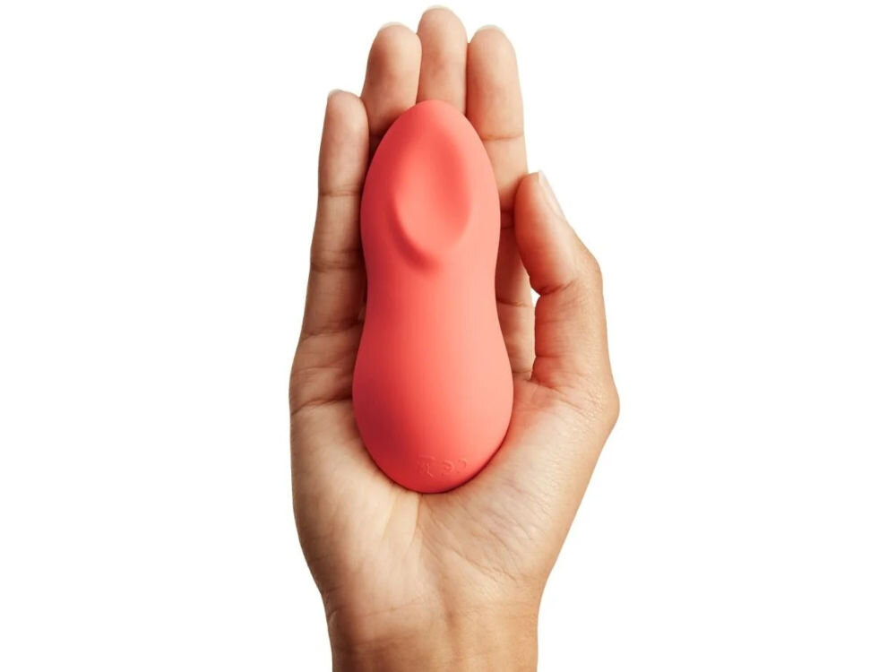 WE-VIBE Touch X Crave Coral masażer wielofunkcyjny koralowy wibrator lezy na dłoni białe tło kompaktowe wymiary długość to tylko 10,22 cm średnica nie przekracza 3,43 cm poręczny łatwy do przechowywania woreczek do przechowywania 