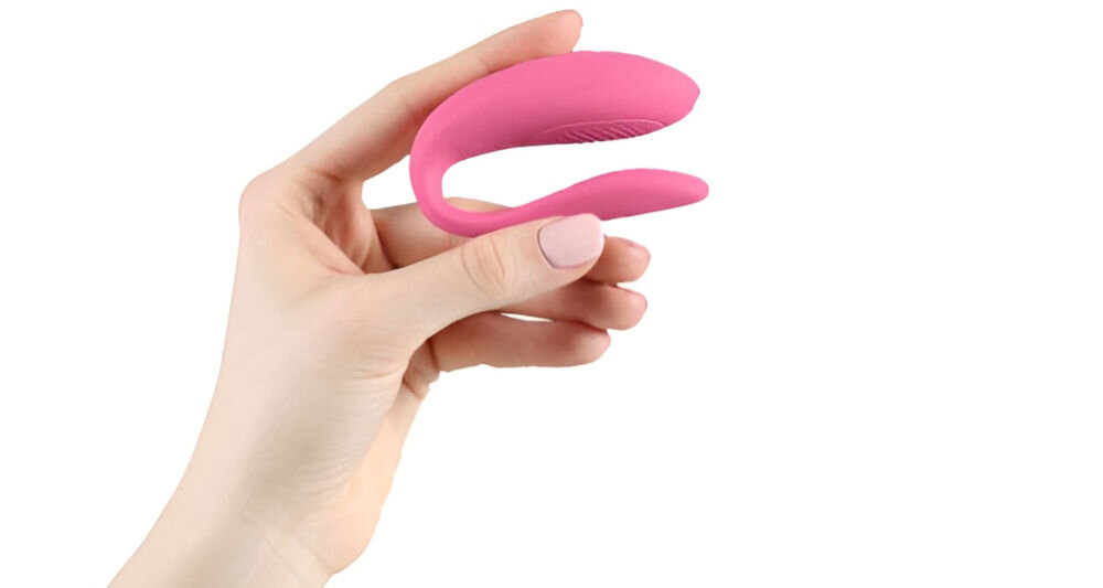WE-VIBE Sync Lite Pink zdalnie sterowany wibrator dla par przyjemne doznania białe tło osoba trzyma w ręku różowy wibrator