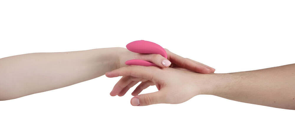 WE-VIBE Sync Lite Pink zdalnie sterowany wibrator dla par białe tło ręka kobiety i mężczyzny kobieta trzyma w ręku różowy wibrator wspólne doznania ergonomiczny kształt przyjemność obojgu partnerom kontakt fizyczny emocjonalny prosta obsługa za pomocą jednego przycisku wygodne korzystanie ponad 10 trybów wibracji pełna personalizacja wrażeń