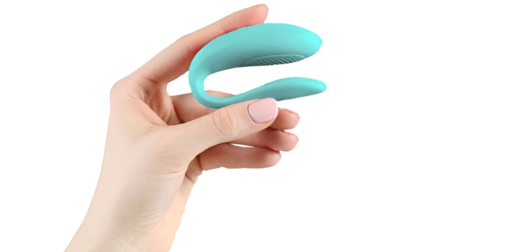 WE-VIBE Sync Lite Aqua zdalnie sterowany wibrator dla par przyjemne doznania białe tło osoba trzyma w ręku niebieski wibrator