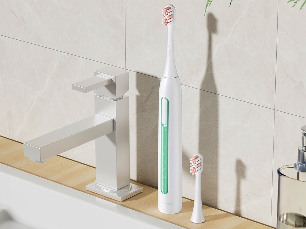 Szczoteczka soniczna ORO-MED Smile Zielony szczoteczka biało zielona obudowa przyciski końcówka włosie stoją na blacie obok zlewu komfort użytkowania ergonomiczny kształt wbudowany timer 30-sekundowe sesje kontrolowanie czasu szczotkowania do 45 dni na pełnym ładowaniu ładowanie przez port USB-A/USB-C około 5 godzin funkcjonalność stylowy wygląd