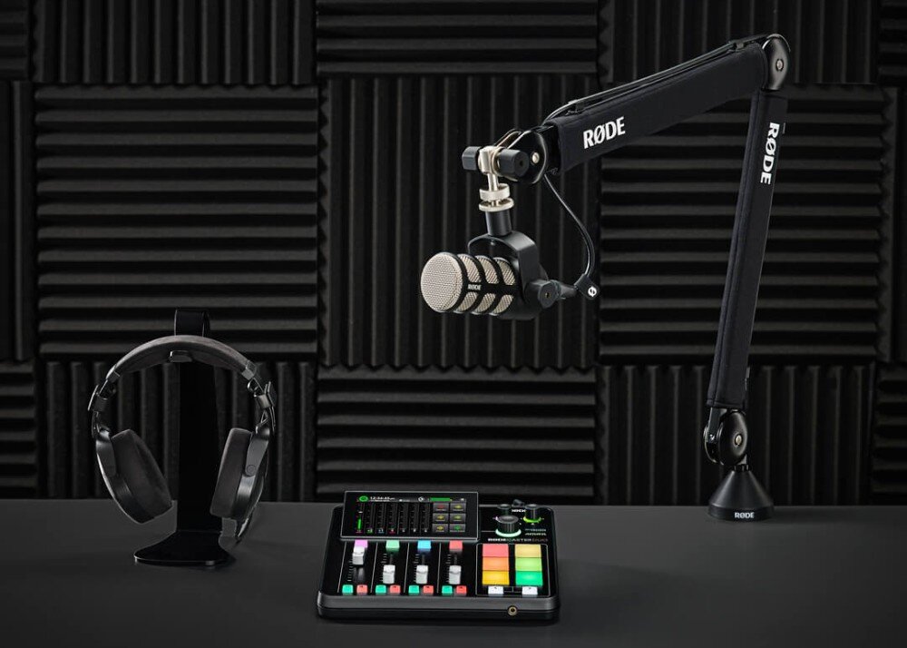 Zestaw RODE Creator Kardioidalny Na tle czarnych paneli akustycznych widoczny mikrofon na ramieniu, stojak ze słuchawkami oraz konsoleta audio z kolorowymi przyciskami i suwakami, przeznaczenie, cechy, zestaw