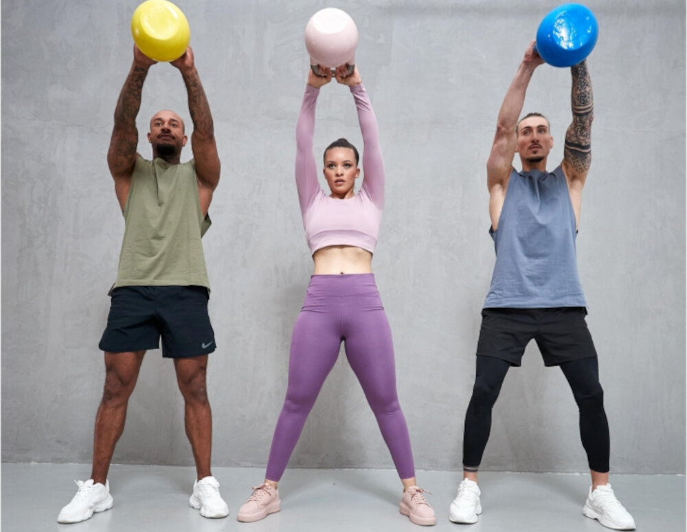 Kettlebell GORILLA SPORTS 2490 (12 kg) szare tło trzy osoby wykonują wznosy trzymają kettlebelle w dłoniach średnica 21 cm wysokość 28 cm do dynamicznych i powolnych ćwiczeń grubość uchwytu około 3,3 cm komfort chwytu precyzyjne prowadzenie ruchu efektywność treningu minimalizuje ryzyko kontuzji