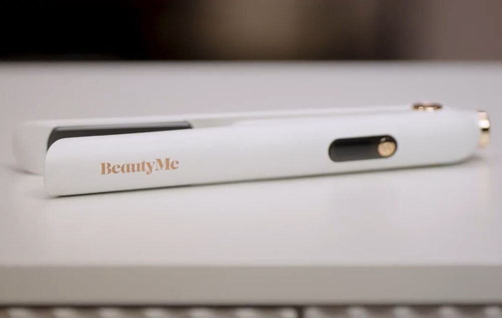 Prostownica bezprzewodowa BEAUTYME HS707W Biała prostownica do włosów BeautyMe HS707W z logo marki, leżąca na jasnym blacie, prezentująca smukły i nowoczesny design urządzenia.