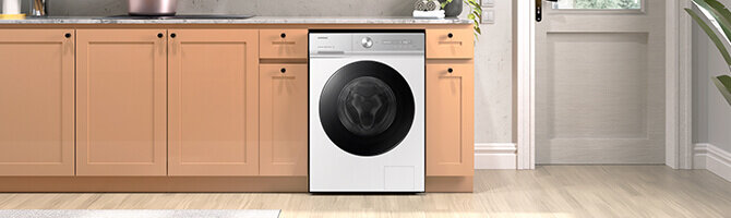 Pralka w zabudowie kuchennej z drewnianymi szafkami, posiada duże, czarne drzwi bębna. Na panelu widoczne są przyciski i pokrętło sterujące.