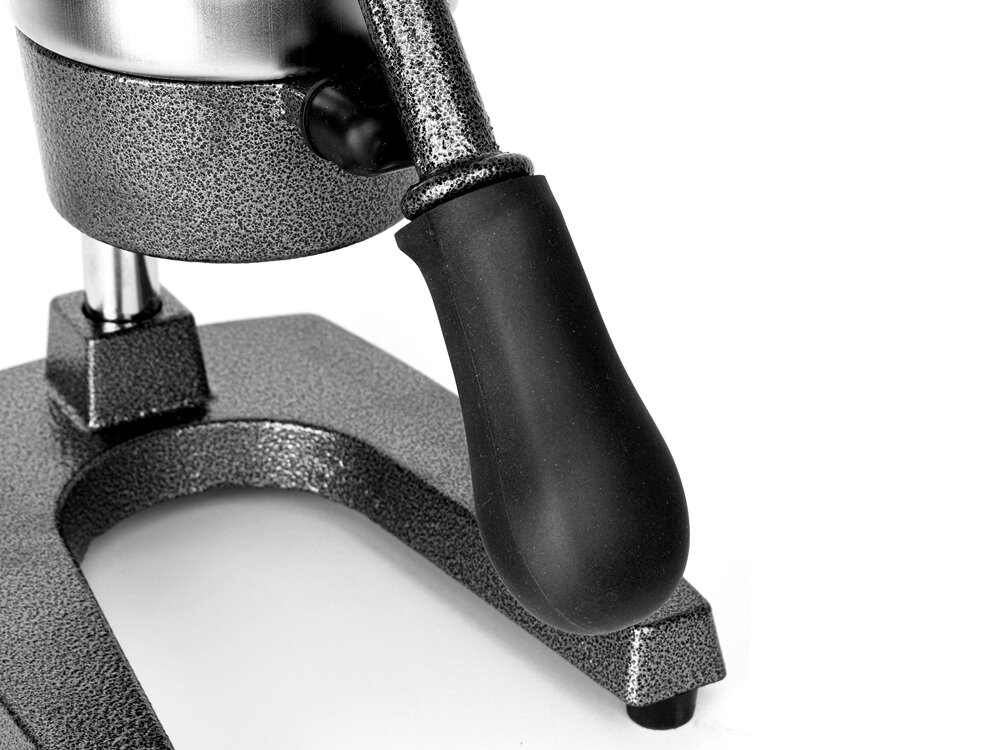 Zdjęcie przedstawia metalową wyciskarkę do cytrusów z czarnym uchwytem. Urządzenie ma solidną, srebrną podstawę z widoczną fakturą.