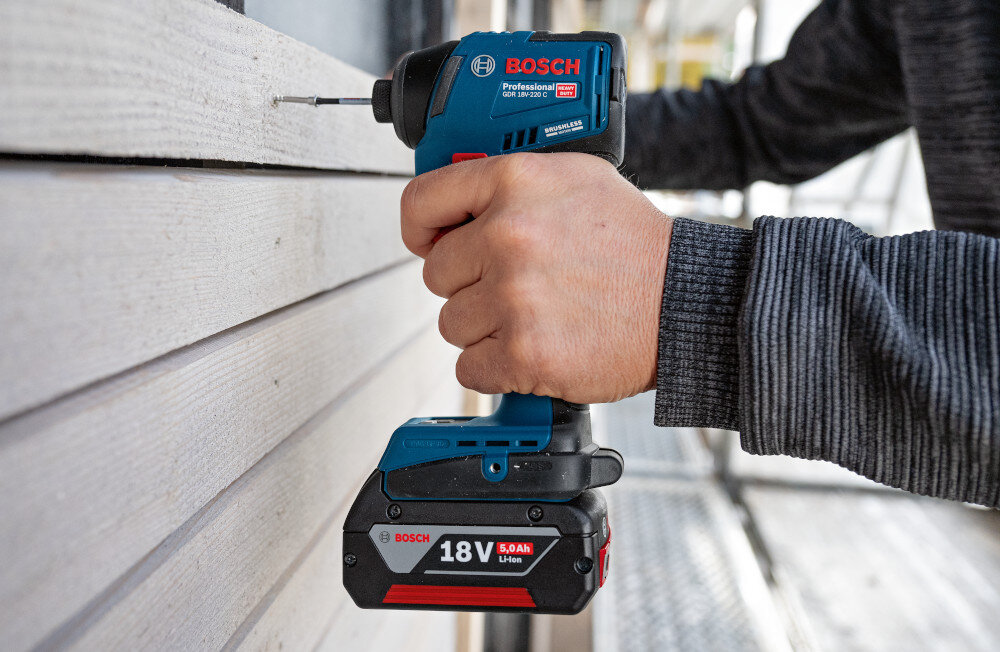 Klucz udarowy BOSCH Professional GDR 18V-220 C 06019L6000 budynek osoba przykręca drewniane deski do ściany budynku trzy zakresy prędkości 800/2300/3400 obr./min trzy ustawienia momentu obrotowego 100/140/220 Nm dopasowanie pracy do materiału i średnicy wkrętu łatwiej kontrolować start i uniknąć zbyt agresywnego dokręcania przyspiesza montaż