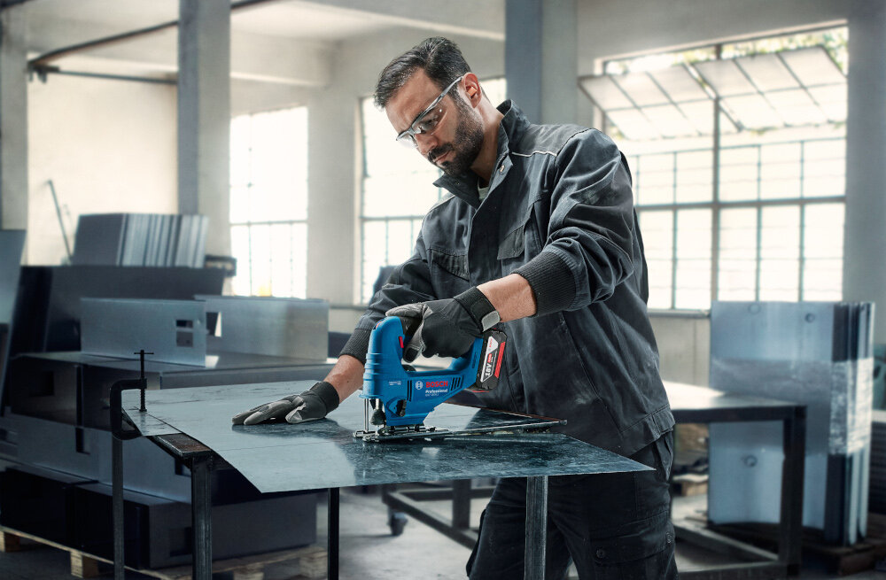 Wyrzynarka BOSCH GST 183-LI Professional pomieszczenie osoba tnie metalową blachę w tle okna wstępny wybór prędkości skokowej dostosowanie tempa pracy do rodzaju materiału kontrola nad narzędziem skrócenie czasu obróbki