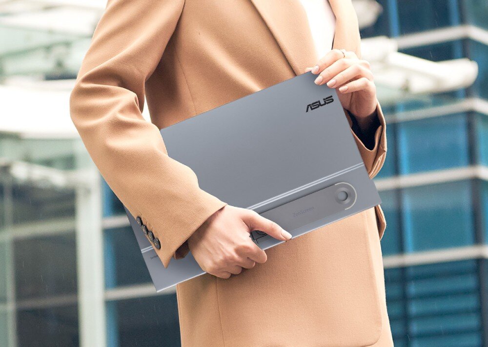 Monitor ASUS ZenScreen MQ16AHE Osoba w płaszczu trzymająca pod pachą zamknięty przenośny monitor w pozycji poziomej, podpórka, gniazda do statywu, ustawienie