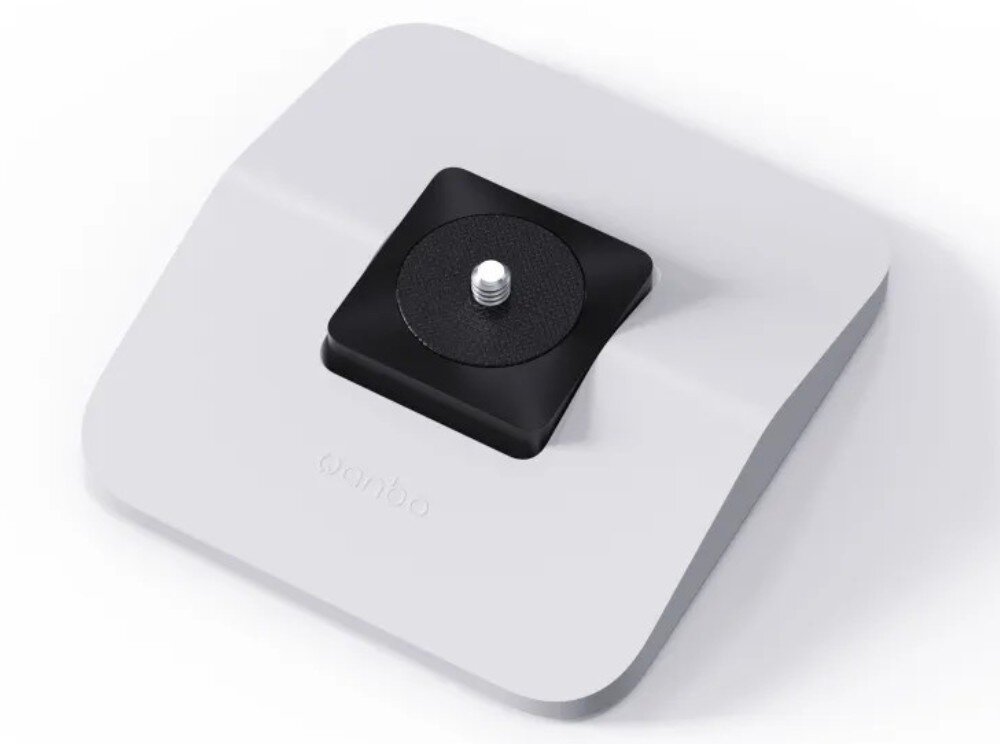 Stojak pod projektor WANBO WBBA02 Widok z góry na jasną, kwadratową podstawkę z zaokrąglonymi rogami, która posiada na środku czarny element z wystającą metalową śrubą montażową