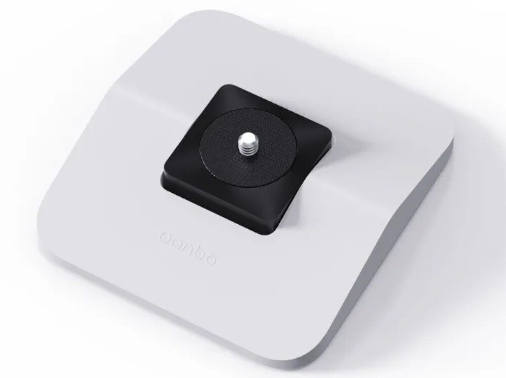 Stojak pod projektor WANBO WBBA03 Widok z góry na jasną, kwadratową podstawkę z zaokrąglonymi rogami, która posiada na środku czarny element z wystającą metalową śrubą montażową