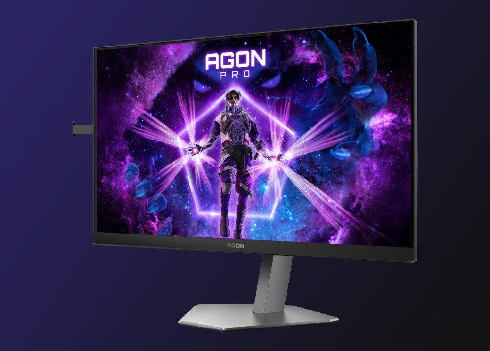 Monitor AOC Agon Pro AG246FK Monitor wyświetlający grafikę z postacią w futurystycznym stroju na tle fioletowej galaktyki z napisem 'AGON PRO' u góry ekranu, opis