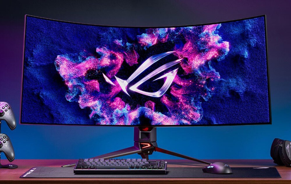 Monitor ASUS ROG Swift PG39WCDM Monitor ustawiony na biurku, wyświetlający grafikę w stylu neonowego pinballa. Wokół znajdują się akcesoria gamingowe, w tym klawiatura, mysz oraz kontrolery do konsol, ochrona wzroku, Flicker-Free, filtr niebieskiego światła, ochrona matrycy