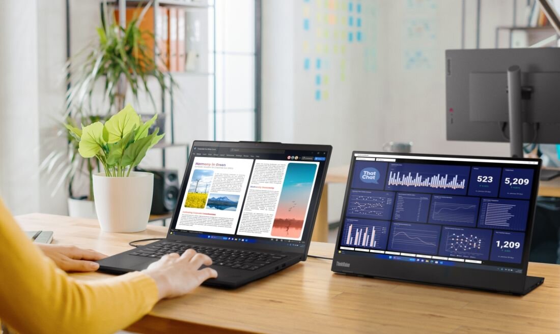 Kobieta w żółtym swetrze pracująca na laptopie Lenovo ThinkPad z dodatkowym monitorem ThinkVision w biurze. - ThinkShield z modułem dTPM