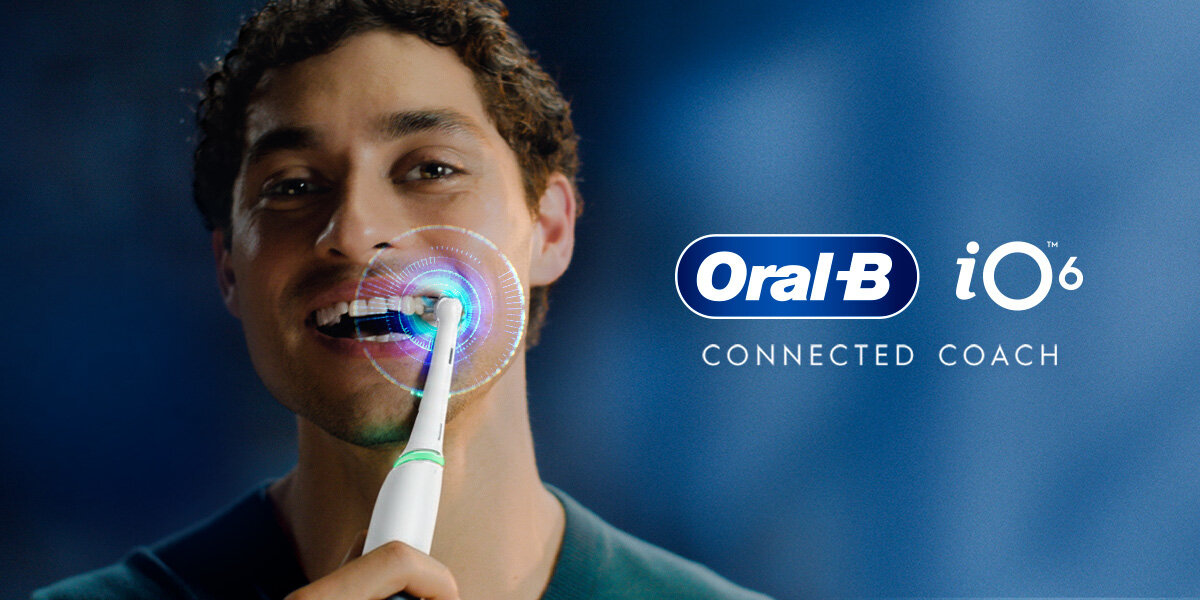 Osoba używa białej szczoteczki magnetycznej Oral-B iO 6, a obok widoczne jest logo Oral-B i napis \'CONNECTED COACH\'.