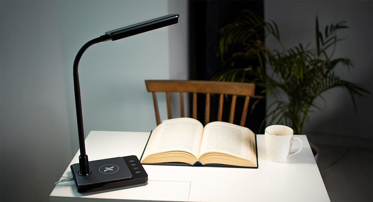 Lampka biurkowa MAXCOM Porto ML3100 czarna, Obudowa, wymiary, przewód, Lampka na biurku włączona, obok książka i doniczka