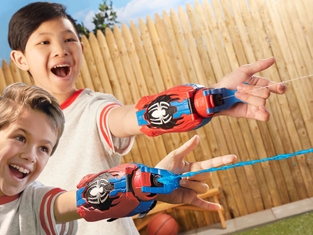 Wyrzutnia HASBRO Marvel Spider-Man Rel Webs F87345L0 Zbliżenie na proces ładowania wyrzutni Nerf Prospect QS-4. Dziecko wkłada niebieską piankową strzałkę do jednej z czterech przednich luf pomarańczowego pistoletu. W dolnej części rękojeści widoczne logo Nerf.