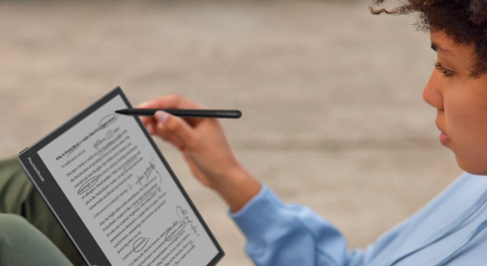 Czytnik e-booków POCKETBOOK InkPad Eo Osoba siedząca na zewnątrz trzyma czytnik i zaznacza tekst na wyświetlanym dokumencie za pomocą rysika, podświetlenie, jasność, barwa podświetlenia