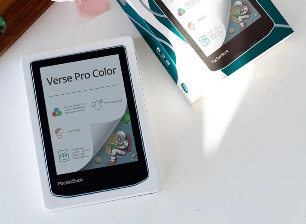 Czytnik e-booków POCKETBOOK Verse Pro Color Czytnik e-booków z ekranem powitalnym specyfikacji technicznej leży na białym blacie obok otwartego pudełka z grafiką urządzenia, ekran, rozdzielczość, kolor