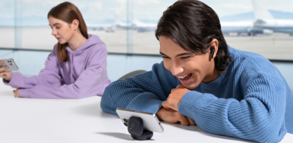 Słuchawki dokanałowe SOUNDCORE P40i ANC etui 2w1 stojak samozamykający, osoba z założonymi słuchawkami dokanałowymi wpatdzona w tleefon zamocowany na etui