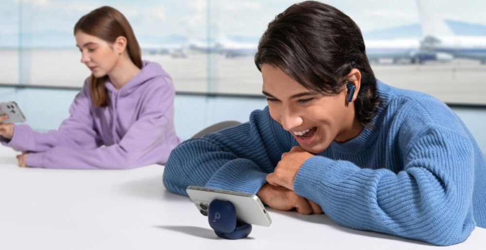 Słuchawki dokanałowe SOUNDCORE P40i ANC etui 2w1 stojak samozamykający, osoba z założonymi słuchawkami dokanałowymi wpatdzona w tleefon zamocowany na etui