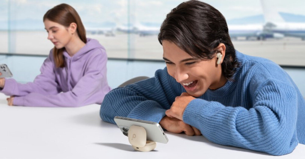 Słuchawki dokanałowe SOUNDCORE P40i ANC etui 2w1 stojak samozamykający, osoba z założonymi słuchawkami dokanałowymi wpatdzona w tleefon zamocowany na etui