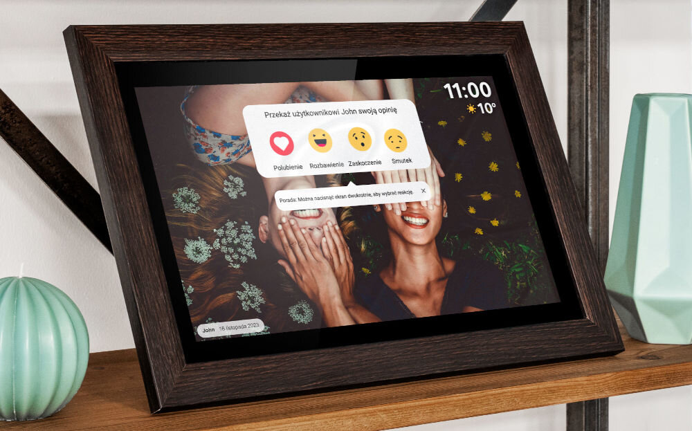 Ramka cyfrowa KRUGER&MATZ KM1102-15 Frameo 15.6 cala Brązowy prezentacja ramki ze zdjęciem i komentarzem na regale obok świeczka i niebieski wazon podłączenie wielu urządzeń jednocześnie dodawanie komentarzy historii emotikon osobiste znaczenie