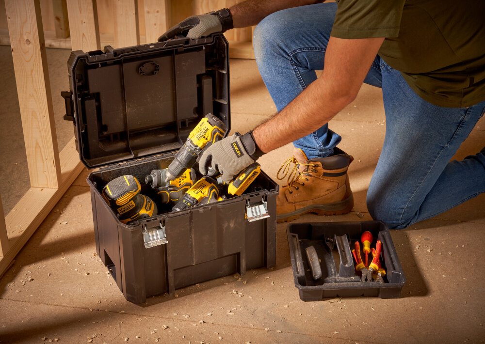 Skrzynka narzędziowa STANLEY Fatmax TSTAK FMST1-75796 pomieszczenie otwarta skrzynka ustawiona na podłodze obok tacka osoba wyciąga z wnętrza wiertarkę wygodne przechowywanie narzędzi i akcesoriów pojemność 22,2 litrów efektywność komfort