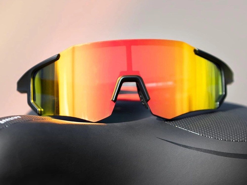 Okulary rowerowe ROCKBROS 10182 Czerwony, UV400, ochrona, promieniowanie, oczy, Okulary sportowe położone na siodełku rowerowym.