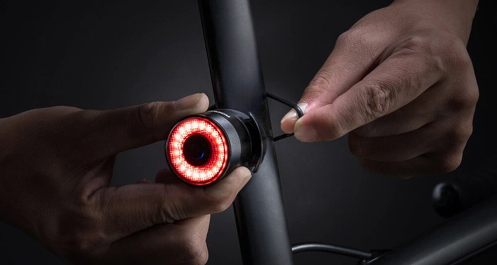 Lampka rowerowa ROCKBROS Q3 ciemne tło osoba mocuje lampkę do roweru 4 tryby świecenia jednostajne, pulsowanie, oddech dynamiczne pulsowanie funkcjonalna w każdej sytuacji czas działania do około 30 godzin