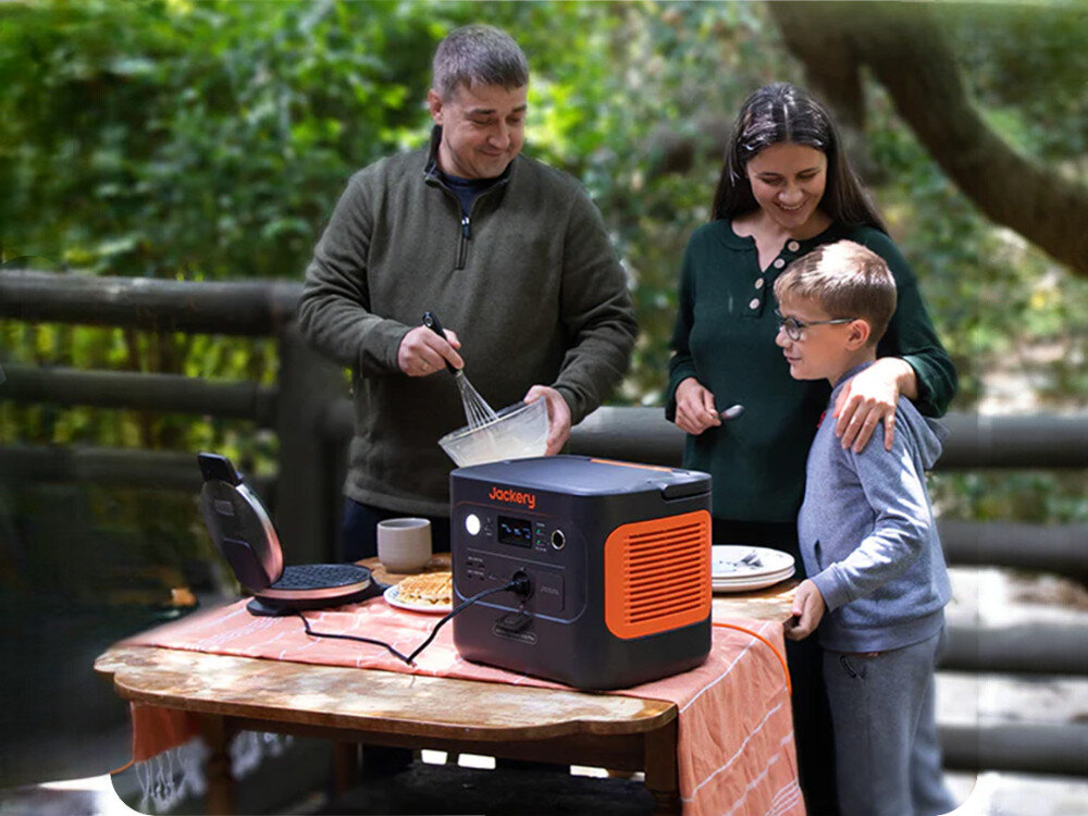 Stacja zasilania JACKERY Explorer 1000 Plus EU 1264 Wh Bank energii, stacja, 1264Wh, LiFePO4, awaria, rodzina stoi przy stole na którym stoi stacja zasilania