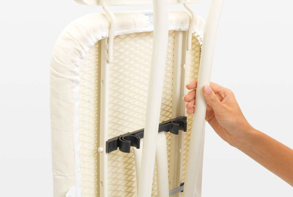 Deska do prasowania BRABANTIA 236129 Denim Grey 124 x 38 cm złożona deska metalowe elementy pokrowiec ręka trzymająca deskę białe tło wygodne przechowywanie i transport blokada transportowa bezpieczne złożenie blokada dziecięca zapobieganie przypadkowemu otwarciu dodatkowe bezpieczeństwo w domu łatwa do przechowywania małe przestrzenie 