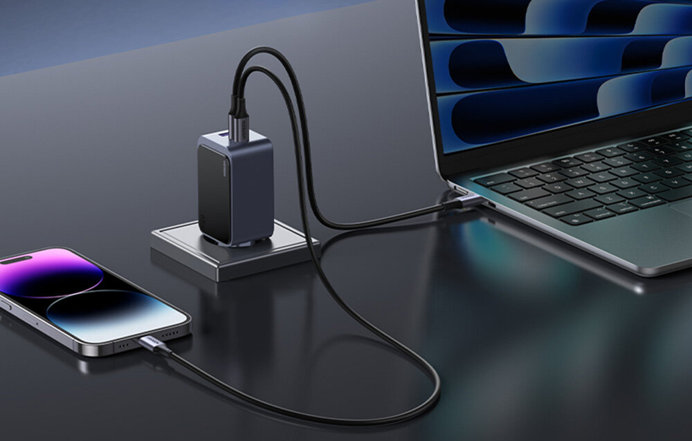 Ładowarka UGREEN wpięta do gniazdka, kable są podłączone do telefonu oraz laptopa.
